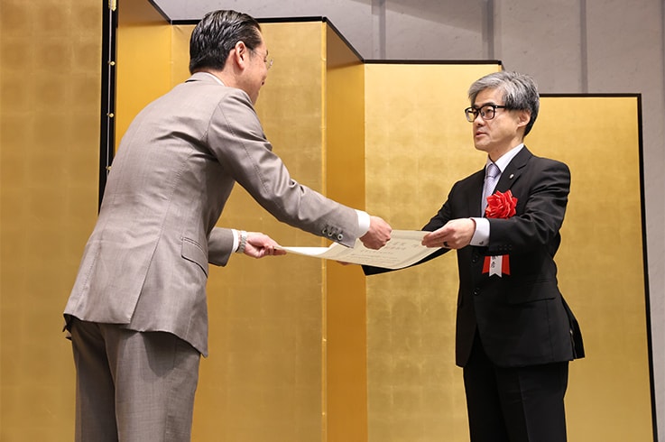 Masahiko Tanaka (General Manager, Industrial Machinery Division) receives the certificate from Taku Kosaka, President of the Nikkan Kogyo Shimbun, Ltd. (Photo provided by Nikkan Kogyo Shimbun, Ltd.)