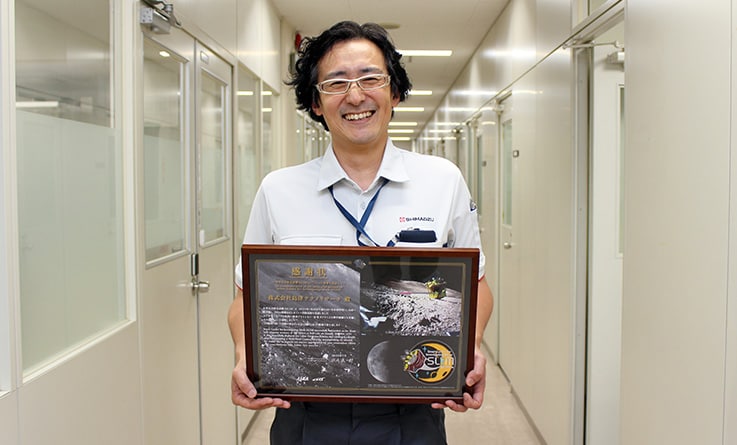 Takashi Nakayama, da Shimadzu Techno-Research, Inc., segurando um certificado de gratidão da JAXA (Vice-gerente, Testing Machine and NDI Group, Analytical & Measuring Instruments Center, Testing Analysis Division)