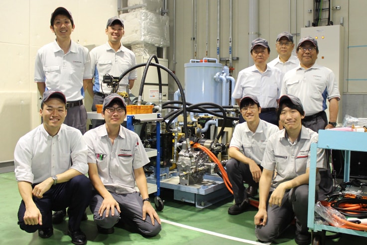 L'équipe de développement avec le système hydraulique motorisé e-Hydro (photo au centre). Goshima est dans la rangée supérieure à l'extrême gauche.