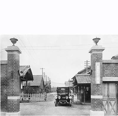 Photo of the main gate from about 1924, showing wooden factories arranged side by side